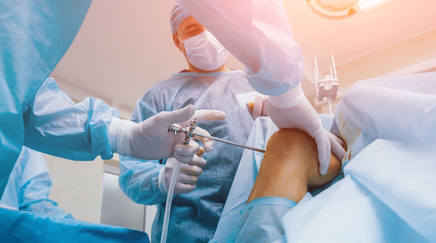 Robotic-assisted surgical system in NHS operating theatre prepared for knee arthroplasty procedure, with surgical team in sterile environment
